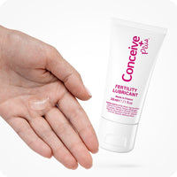 Conceive Plus Max Couples Fertility Bundle featuring a 30ml tube of fertility lubricant with a visible dab of clear gel dispensed onto an open palm, emphasizing product texture and application, displayed on a white background.